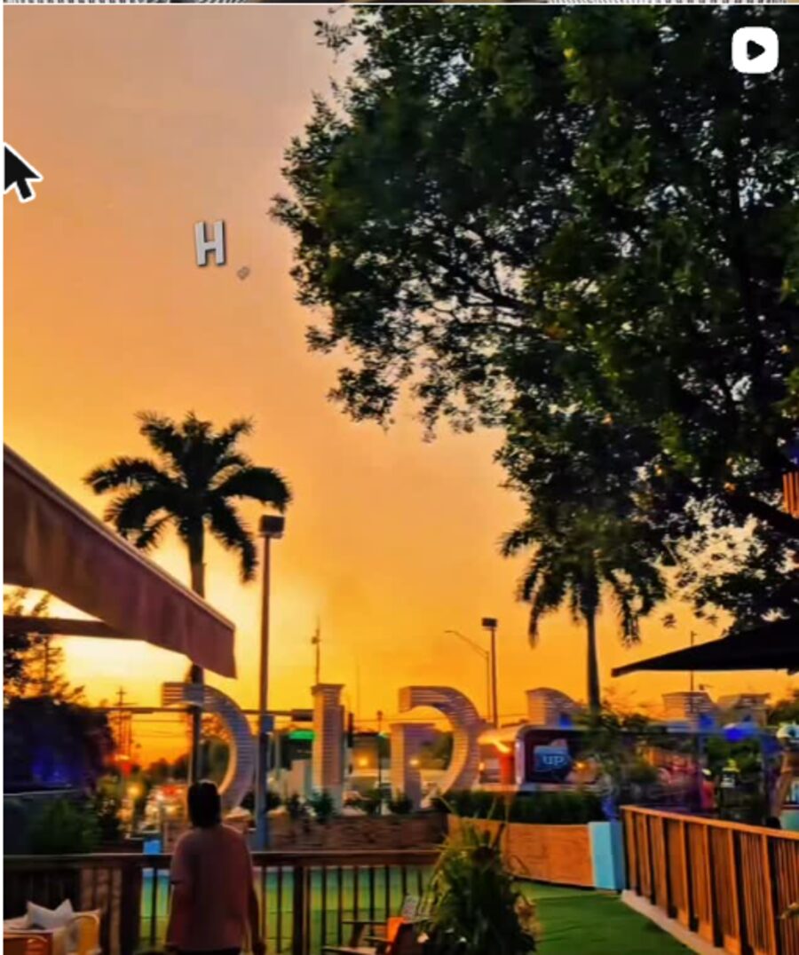 The Triangle at Little River outdoor venue at sunset, with palm trees, string lights and the venue's marquee sign
